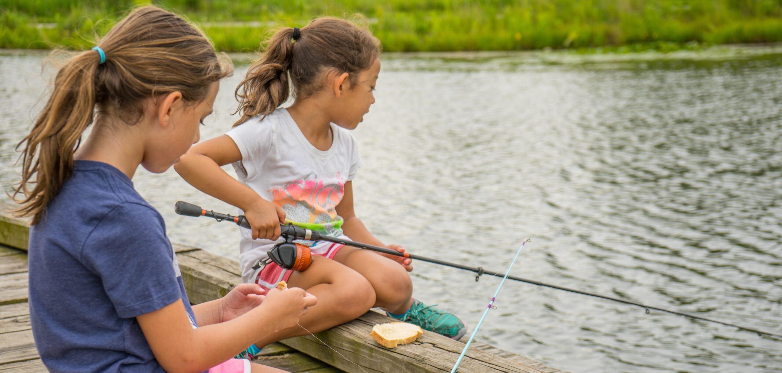 Two girls fishing as the cover for the 2025 Summer Program Guide